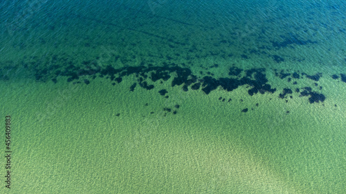 Luftaufnahme vom klarem Meer mit Steinen und Seegras am Grund