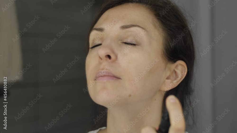 Young woman is spraying the micellar water on her face at the bathroom. High quality 4k footage Young woman is spraying the micellar water on her face at the bathroom. High quality 4k footage