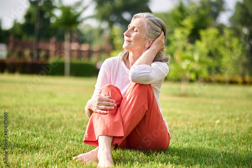 Woman with closed eyes sunbathing on lawn photo