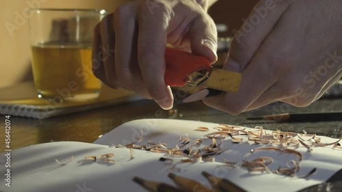Close up Hands are sharpening a simple pencil with a knife.
