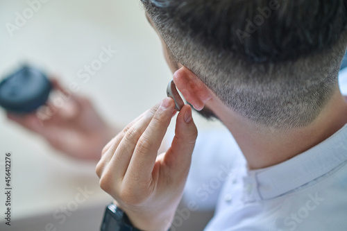 Doctor testing hearing aid in his ear