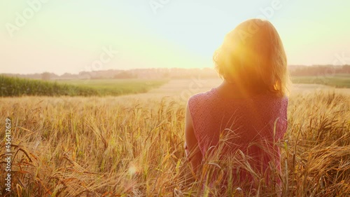 A woman relaxes on the field looking at the sunset. Rest at nature.