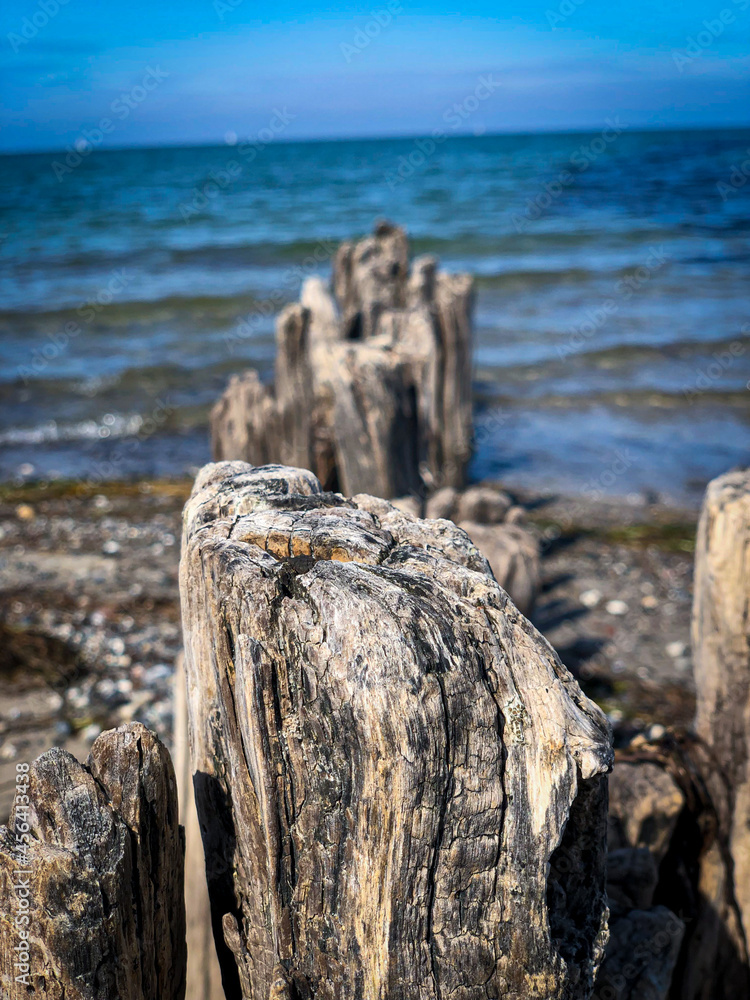 Alte Holzpfähle am Strand direkt ins blaue Meer übergehend