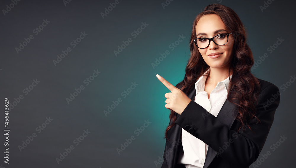 Portrait of a beautiful European businesswoman of the 30s in official clothes and glasses pointing fingers to the side, Studio portrait of an elegant and elegant brunette classic style of clothing Portrait of a beautiful European businesswoman of the 30s in official clothes and glasses pointing fingers to the side, Studio portrait of an elegant and elegant brunette classic style of clothing