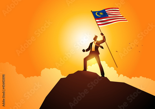 Businessman optimistically standing on a mountain holding the flag of Malaysia