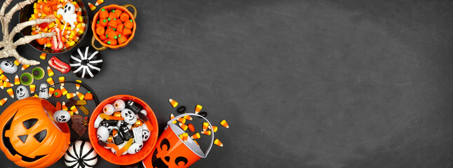 Halloween trick or treat corner border with jack o lantern pails and a variety of candy. Above view on a black banner background with copy space.