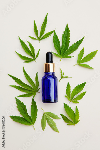 Green fresh hemp leaves, oil in blue bottle on white background. Medical marijuana. Concept of herbal alternative medicine, cbd oil, pharmaceptical, cosmetic industry. Copy space.