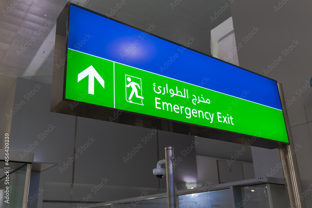 Emergency exit sign in English and Arabic glowing green at airport Emergency exit sign in English and Arabic glowing green at airport
