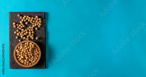 Chickpeas on slate surface and cork bowl on blue background. Flat lay. Copy space.