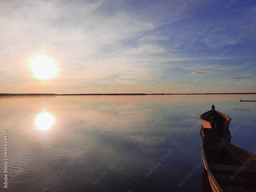Shatsky Lakes. Ecotourism. Shatsk National Natural Park. Landscape of the setting sun on the lake. Blue skies and gentle water with sun tints. The mirror water of the lake reflects the sky.