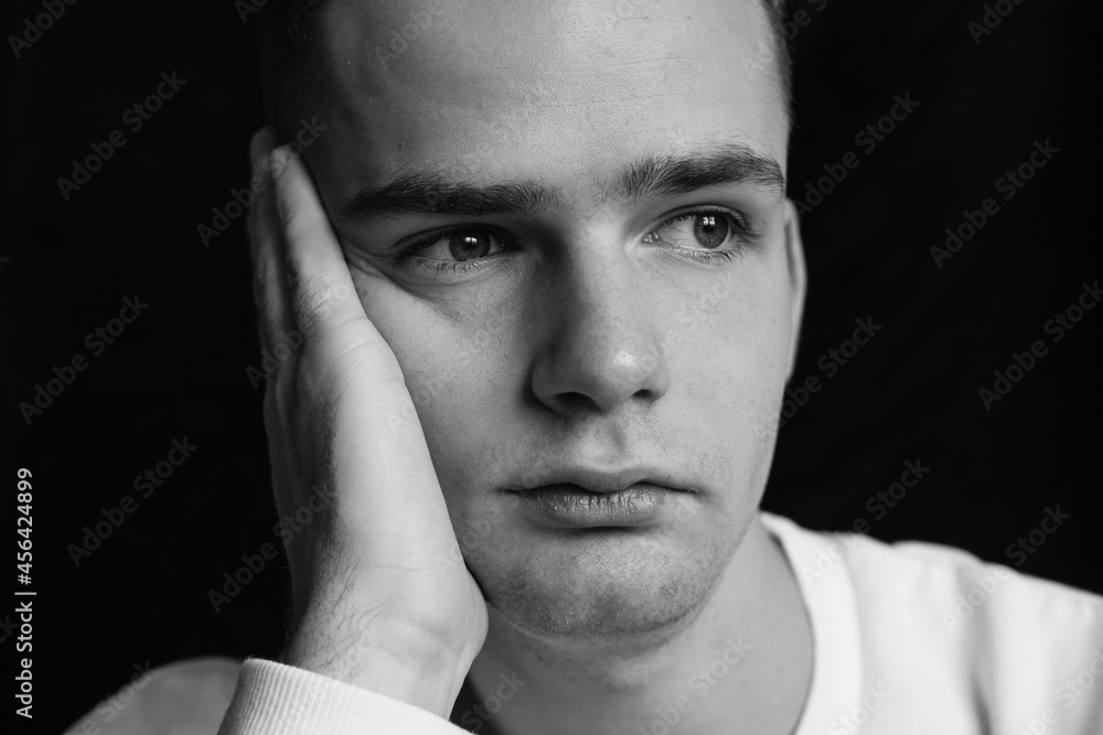 sad young guy, teenager holding his head, black and white photo