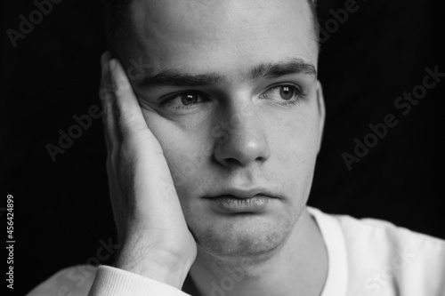 Obraz na płótnie sad young guy, teenager holding his head, black and white photo w salonie