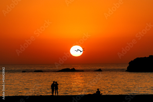 Colorful Sunset Over Ocean with people on the Beach