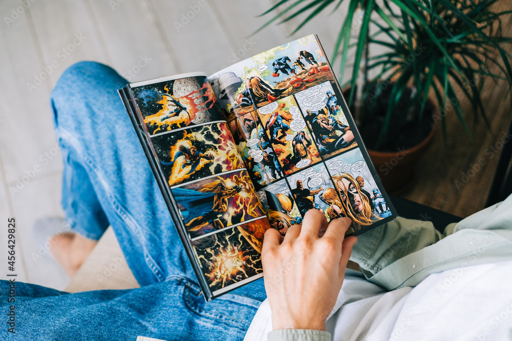 Obraz premium Man reads comic book in living room at home. Rostov-on-Don, Russia. 8 September 2021