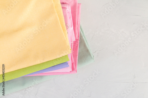Stack of colorful cotton fabric against grey background, slow fashion and home sewing concept