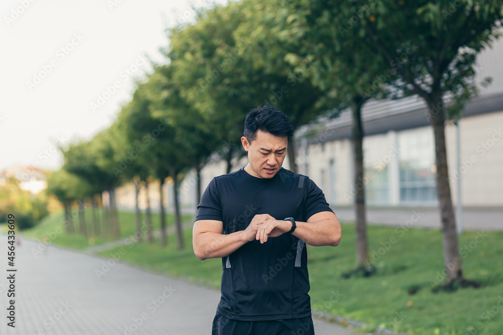 Obraz premium Male asian athlete, tired after a morning jog, runs in the park near the stadium