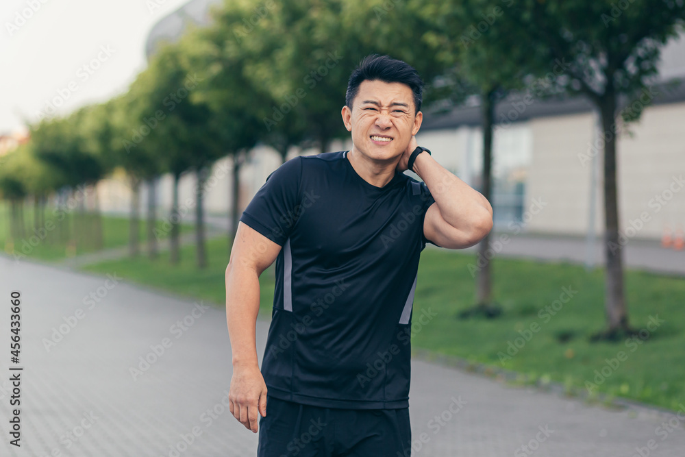 Male asian athlete, running in the park in a backpack before work, running in the park near the stadium has severe neck pain tired of pain Male asian athlete, running in the park in a backpack before work, running in the park near the stadium has severe neck pain tired of pain