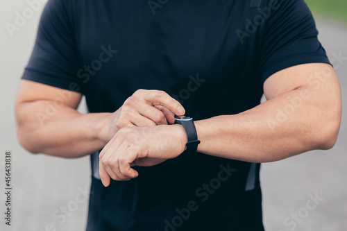 Close-up photo of a male athlete choosing a sports program on a fitness bracelet