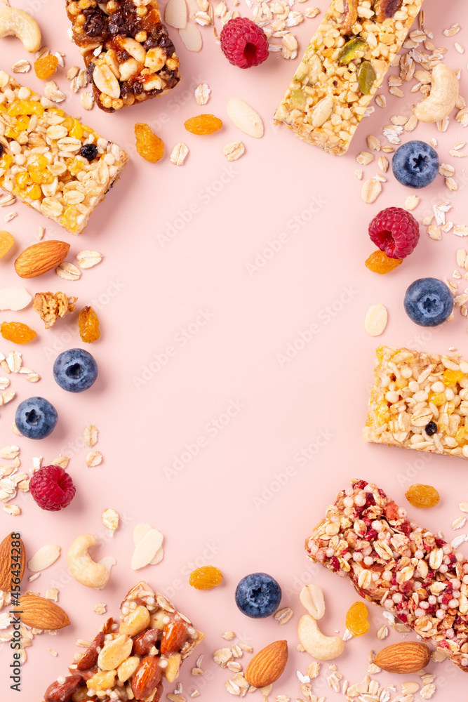 Fototapeta Granola bars. Healthy energy bars made of cereals, berries, nuts and fruits on a light pink background. Space for the text. Top view.
