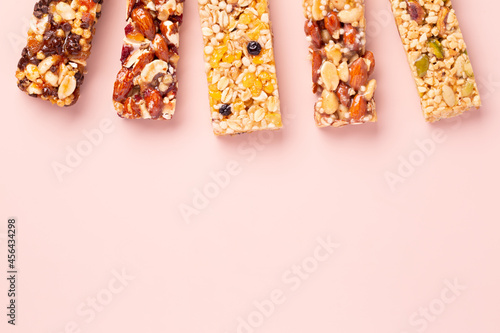 Granola bars. Healthy energy bars made of cereals, berries, nuts and fruits on a light pink background. Space for the text. Top view.