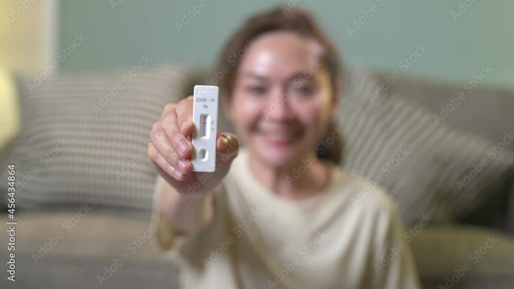Asian woman using rapid antigen test kit for self test COVID-19 epidemic at home. Adult female showing negative results of COVID-19 on test strip. COVID-19 coronavirus pandemic protection concept Asian woman using rapid antigen test kit for self test COVID-19 epidemic at home. Adult female showing negative results of COVID-19 on test strip. COVID-19 coronavirus pandemic protection concept