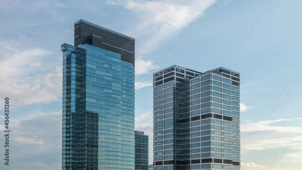 Timelapse skyscrapers, high office buildings facades, blue sky and clouds moving fast in time-lapse reflected on windows surface glass. Time lapse downtown financial district, modern city background Timelapse skyscrapers, high office buildings facades, blue sky and clouds moving fast in time-lapse reflected on windows surface glass. Time lapse downtown financial district, modern city background