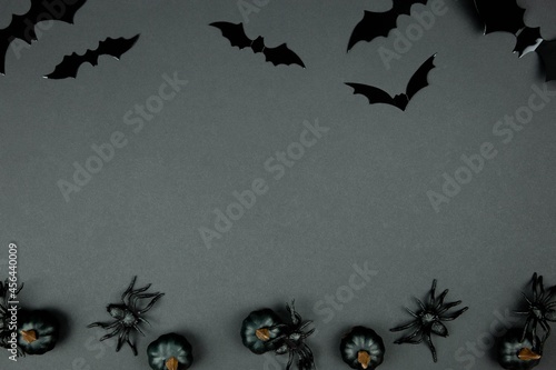 Happy halloween flat lay composition with black pumpkins, spiders and bats on dark background. Holiday concept. Top view. Copy space.
