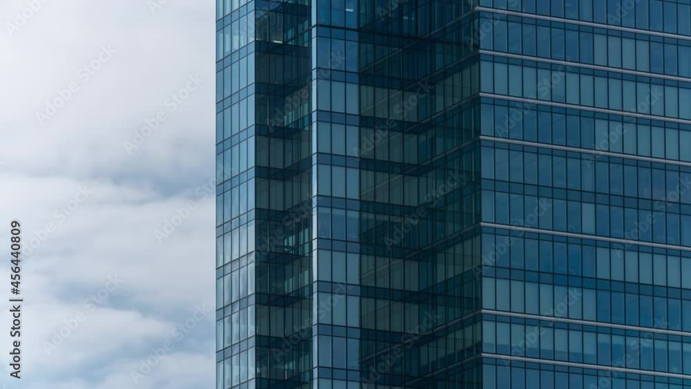 Timelapse close-up glass skyscraper high office building facade, blue sky and clouds moving fast reflected on surface structural windows glass. Reflection time lapse downtown financial district Timelapse close-up glass skyscraper high office building facade, blue sky and clouds moving fast reflected on surface structural windows glass. Reflection time lapse downtown financial district