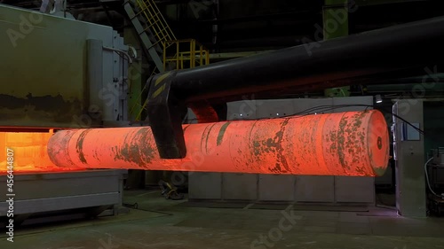 The process of excavation of a metal hot red blank from a furnace at a mechanical plant. Metallurgical industry, production of pipes from zirconium, titanium. photo