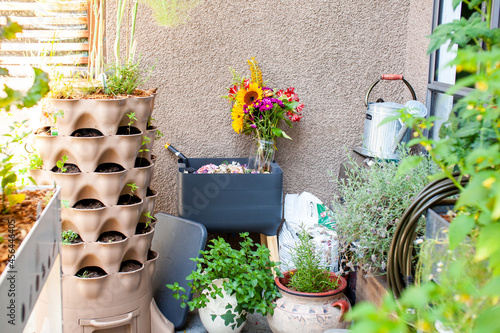 A busy patio (balcony) garden is filled with vegetables, herbs and flowers. A vertical garden tower sits in one corner, and a worm composter (vermicomposting) recycles food and garden waste photo