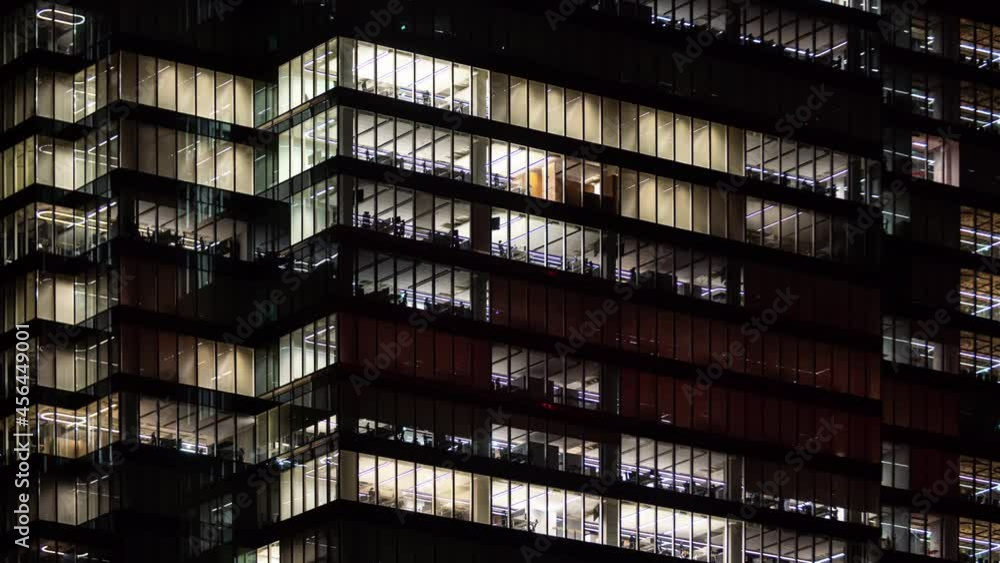 Time lapse people working late night, office windows light in business center building facade. Corporate business, high skyscraper glass surface. Lights in building windows turn on and off Time lapse people working late night, office windows light in business center building facade. Corporate business, high skyscraper glass surface. Lights in building windows turn on and off