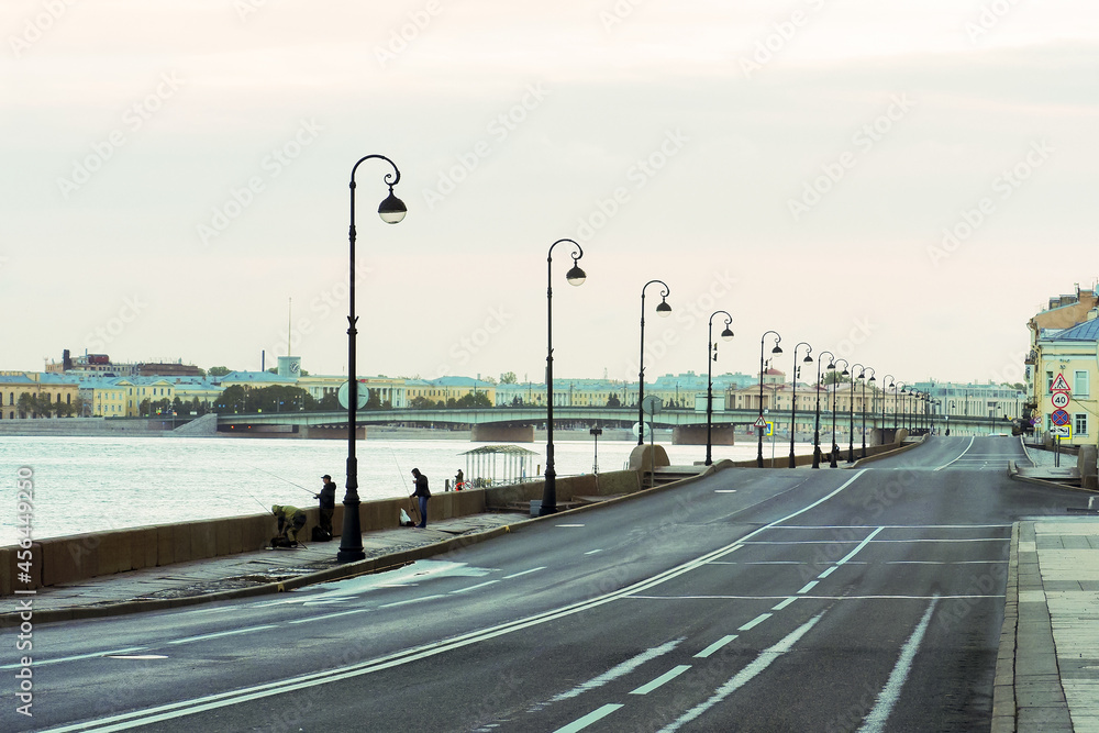 Deserted streets of the city center at sunrise, St. Petersburg, Russia. Lonely fishermen on the embankment of the Neva river