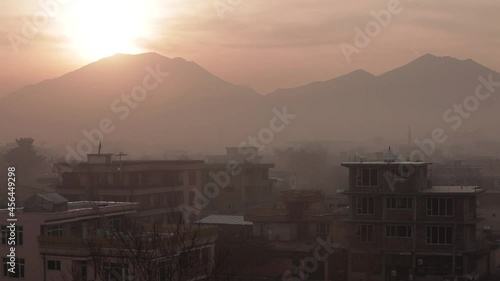 Afghanistan scene - sunrise over Kabul city - with buildings - and he sun gleaming over a large mountain top photo