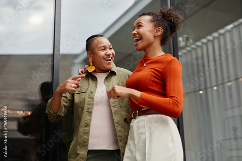 Waist up portrait of two young women laughing carefree white enjoying outdoor party at rooftop