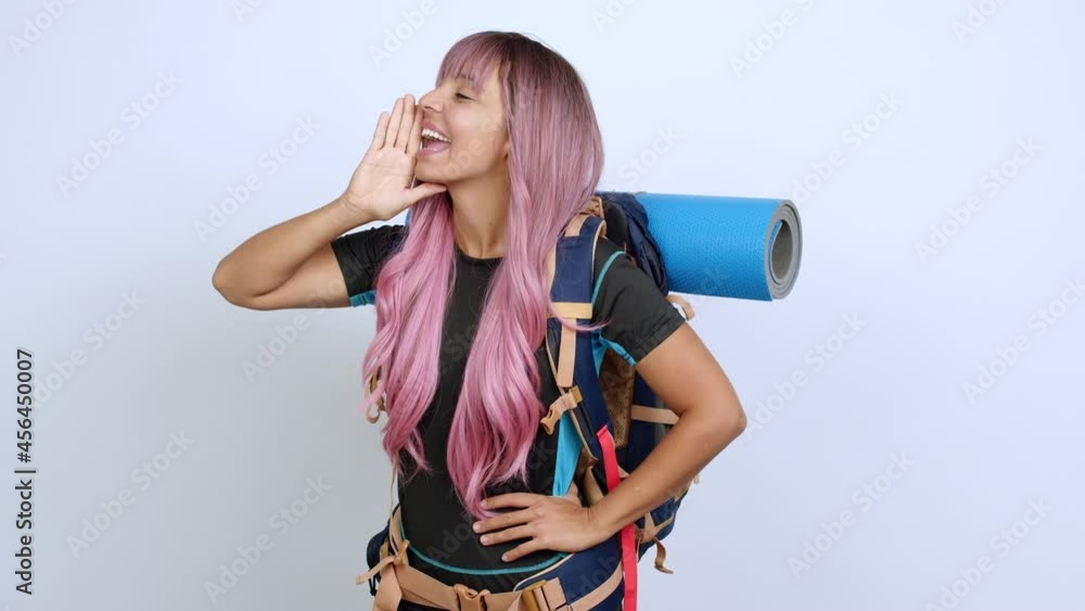 Young woman with pink hair with mountaineering backpack shouting to the lateral and announcing something over isolated background Young woman with pink hair with mountaineering backpack shouting to the lateral and announcing something over isolated background
