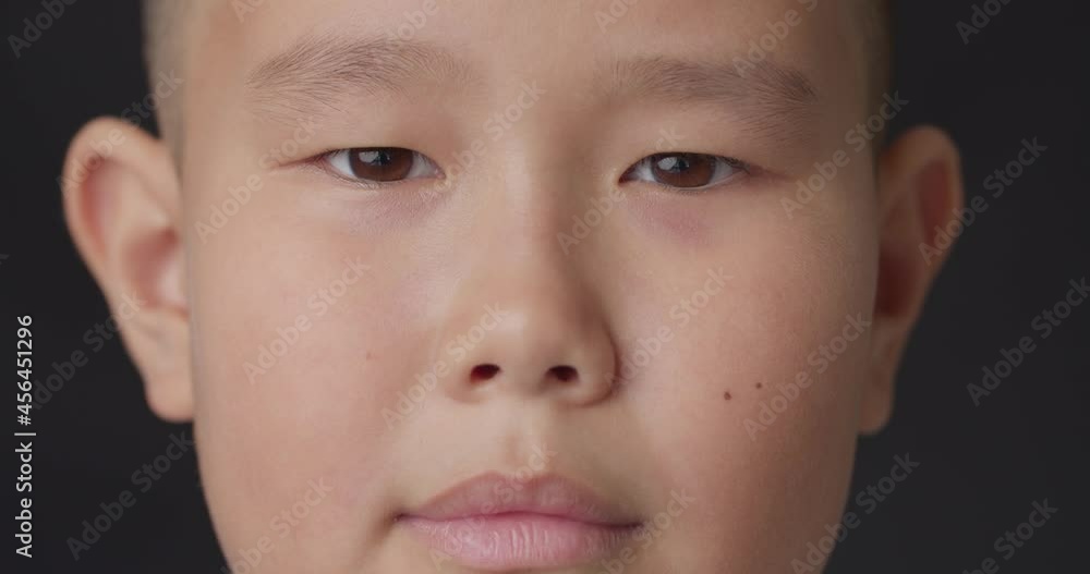 Cute smiling Asian boy on dark background, closeup Cute smiling Asian boy on dark background, closeup