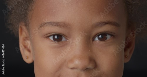 Happy smiling African-American girl on dark background, closeup