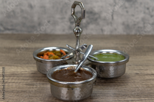 Flavor enhancing condiments with silver serving spoon and round cannisters for easy variety choice of seasoning for your food