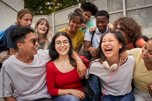 A girl surrounded by classmates looking at a smiling camera. Happy students in high school.