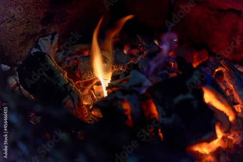 Glowing coals in a barbeque grill and a little flame
