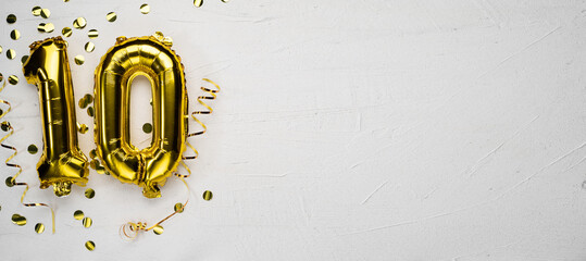 golden foil balloon number ten. Birthday or anniversary card with the inscription 10. gray concrete background.
