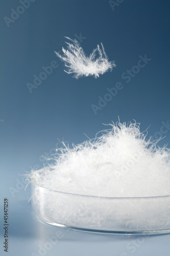 white down feathers in a dish on blue background.