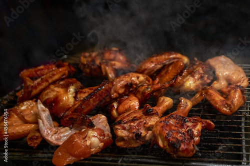 Tasty chicken legs and wings on the grill with smoke