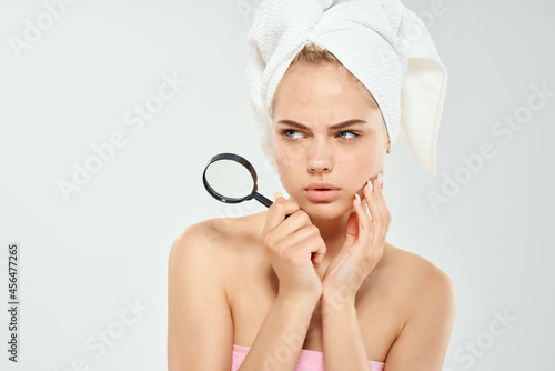 woman with bare shoulders with a magnifying glass in her hands black dots on her face