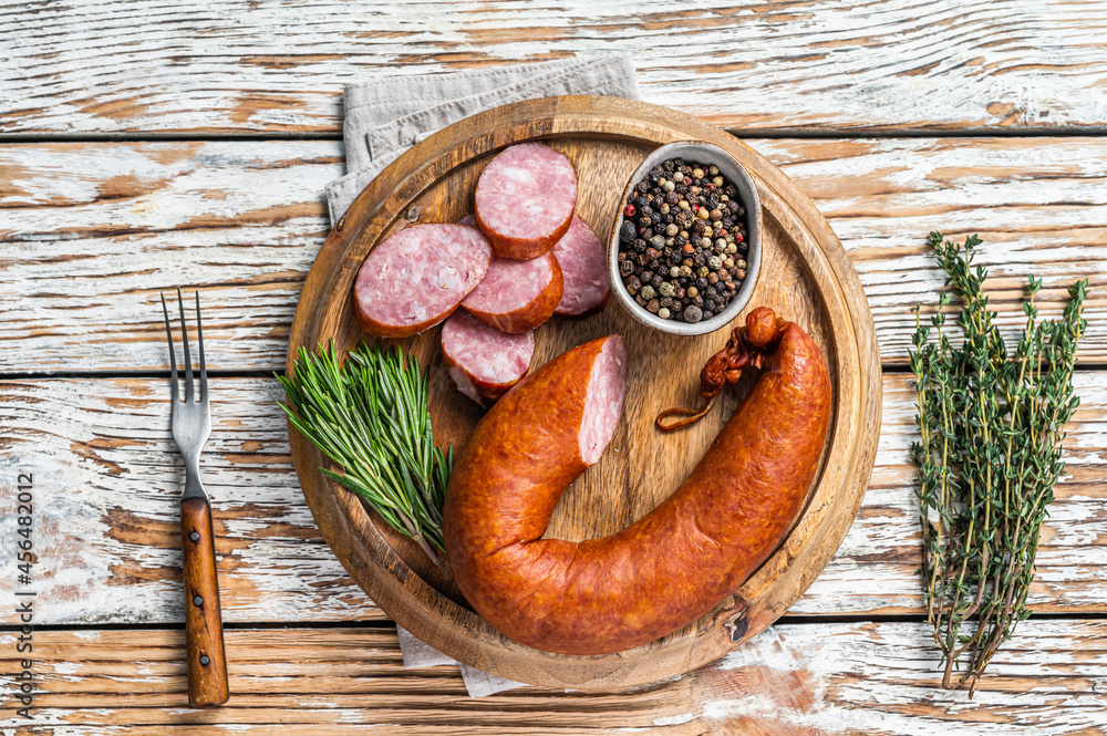 Bavarian Smoked sausage on a wooden board with herbs. White wooden background. Top view