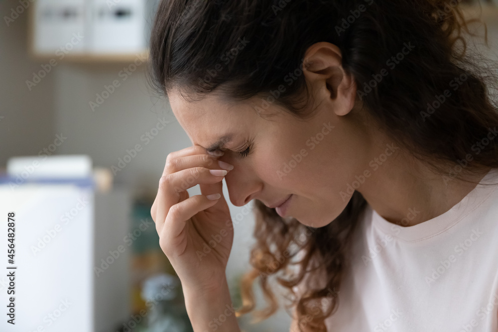 Sick sad woman closed eyes touching nose bridge suffers from headache, eye strain emotional stress. Pressure, panic attack, migraine, life troubles, information overloading concept Sick sad woman closed eyes touching nose bridge suffers from headache, eye strain emotional stress. Pressure, panic attack, migraine, life troubles, information overloading concept
