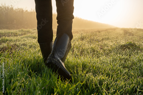 Cropped shot of farmer wearing in rubber boots walking in the field