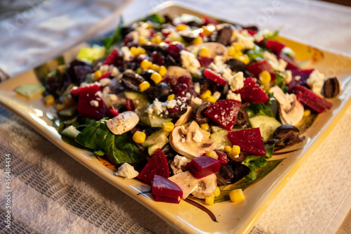 tasty and fresh salad for lunch plated with beets, spinach, mushrooms, black olives, corn and feta cheese for a colorful culinary homemade dish