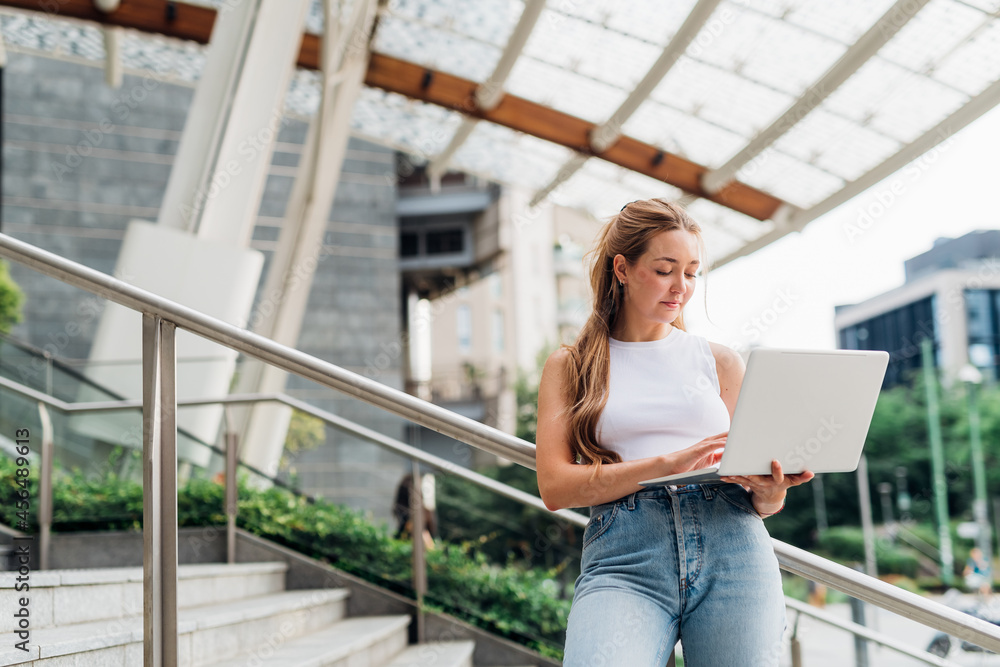 Fototapeta premium Contemporary caucasian business woman outdoor posing using computer smiling satisfied