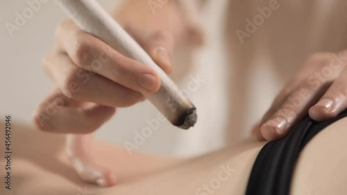 Alternative therapist applying moxibustion a traditional chinese medicine method. Doctor healing young patient with traditional asian medicine. Moxa stick alone. Extreme close up. Moxibustion.